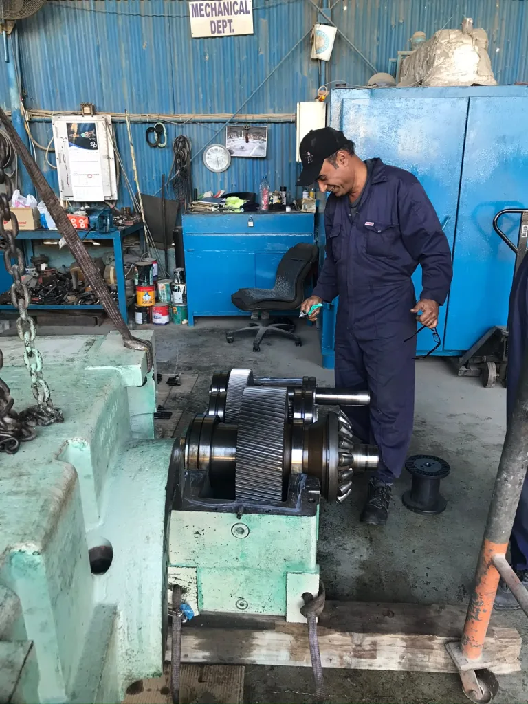 Technician working on an opened gearbox with helical gears during overhaul
